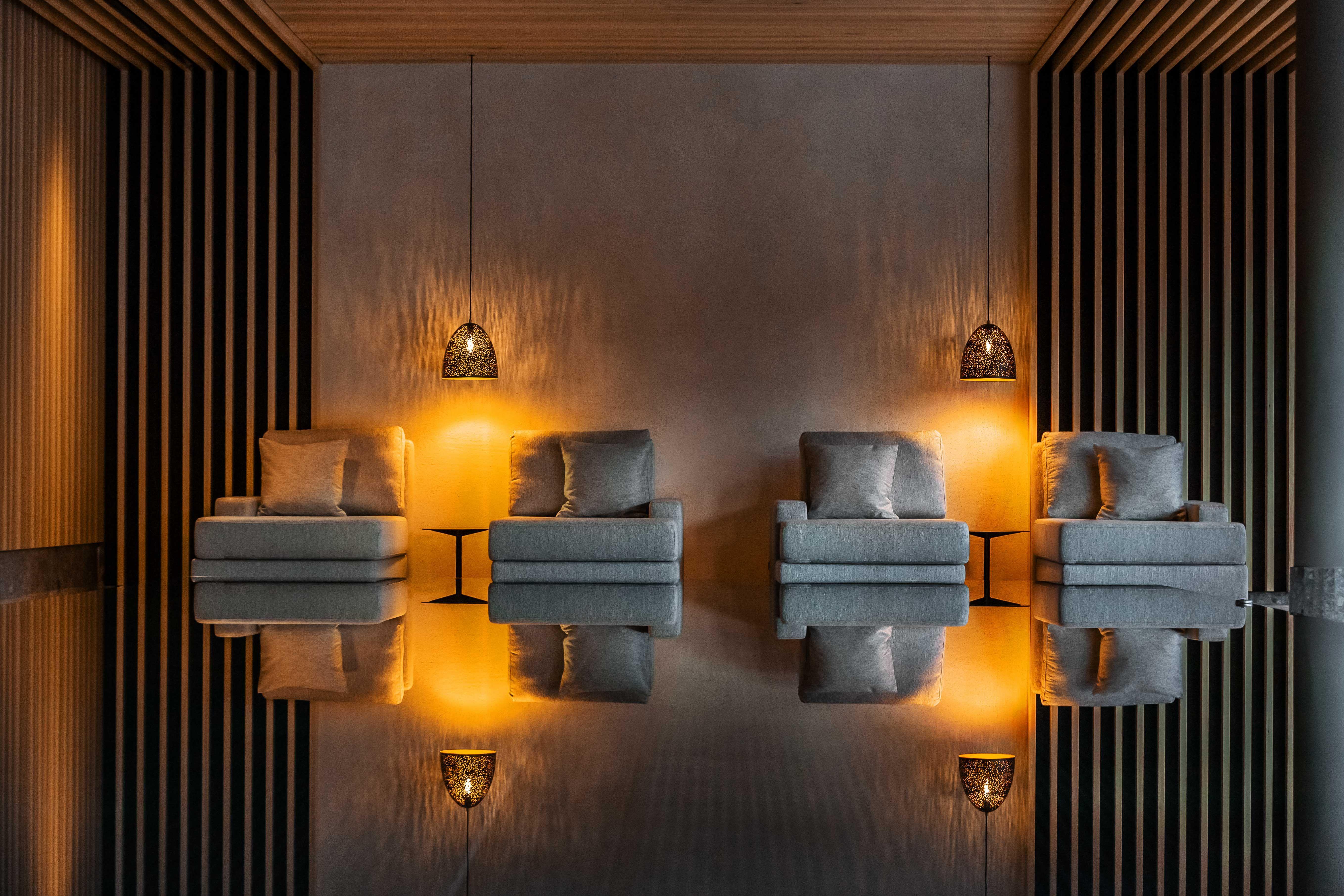 architectural photo of an indoor pool with lounge chairs in a mood lighting.