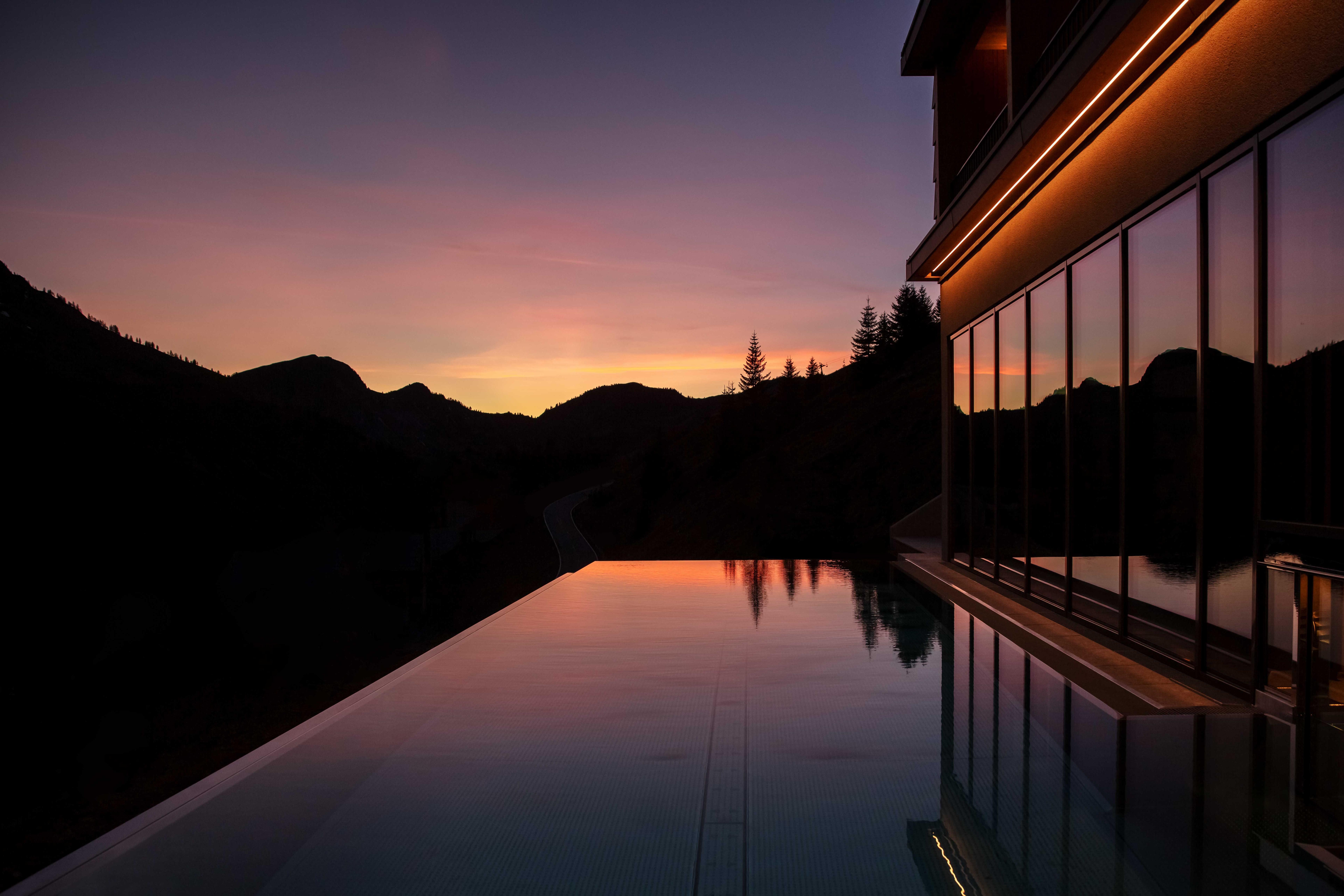 outdoor infinity pool after sunset under the pink sky.