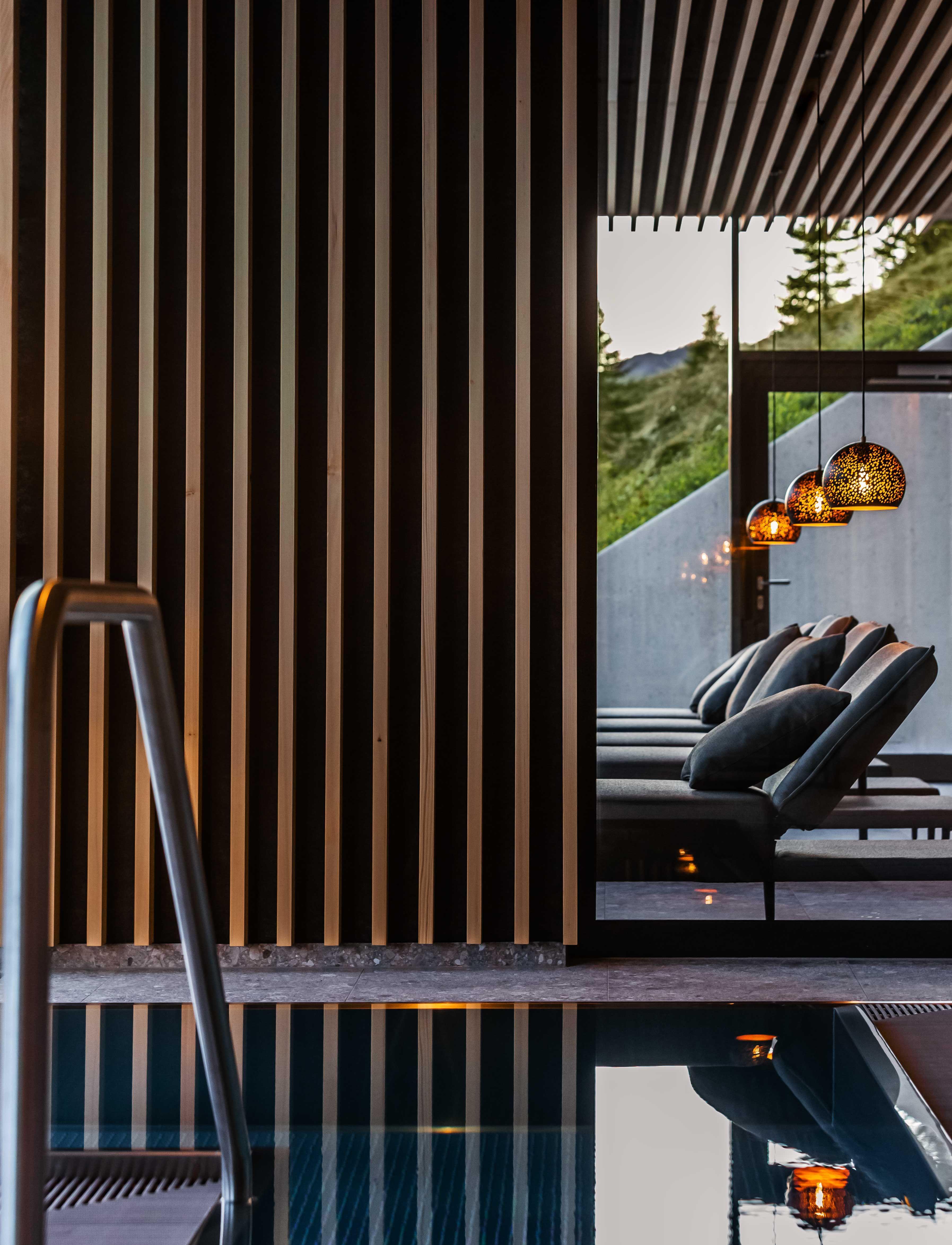 detail of an indoor pool with deck chairs and lights.