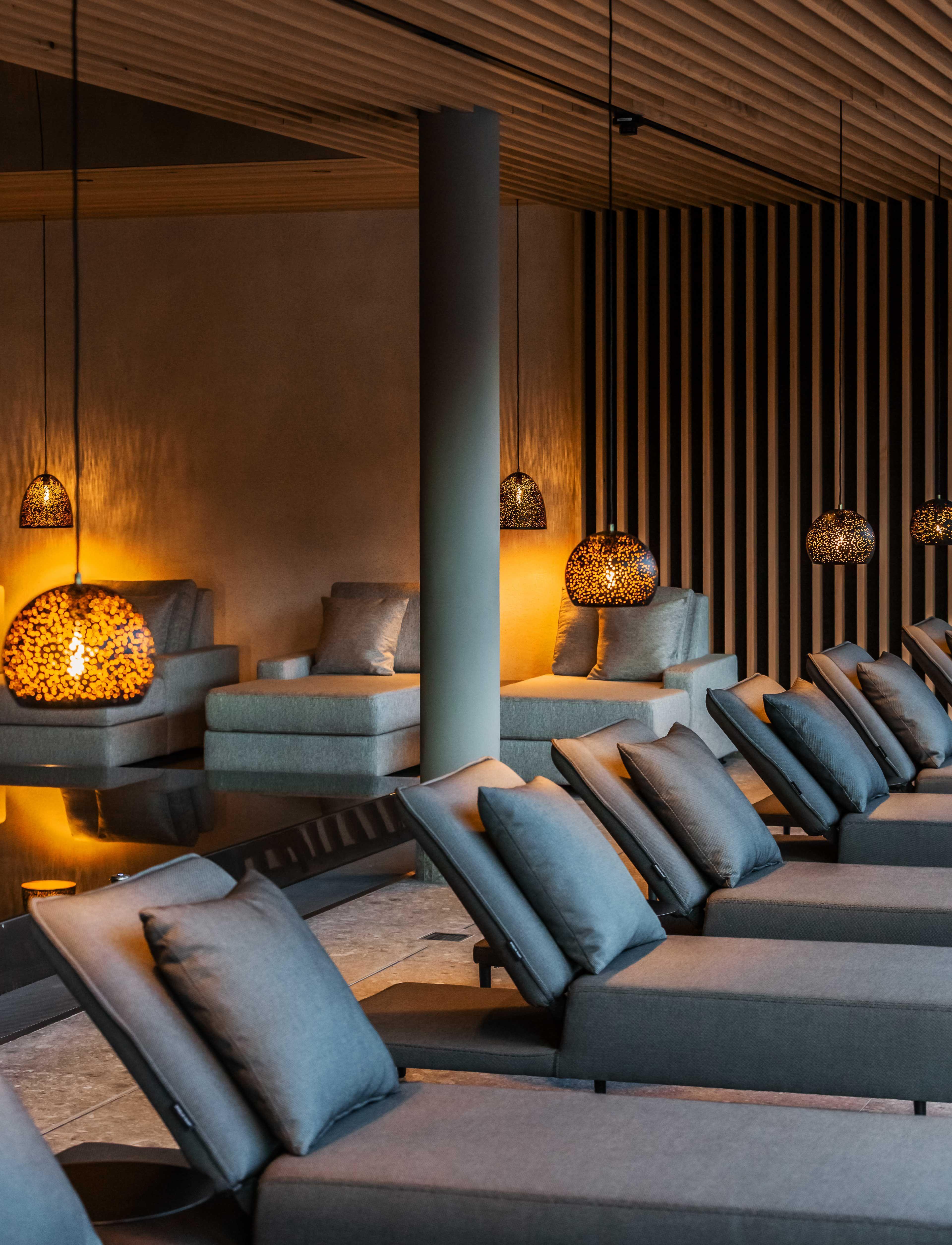 interior shot of several couches arranged around an indoor pool with some gold shining lamps.