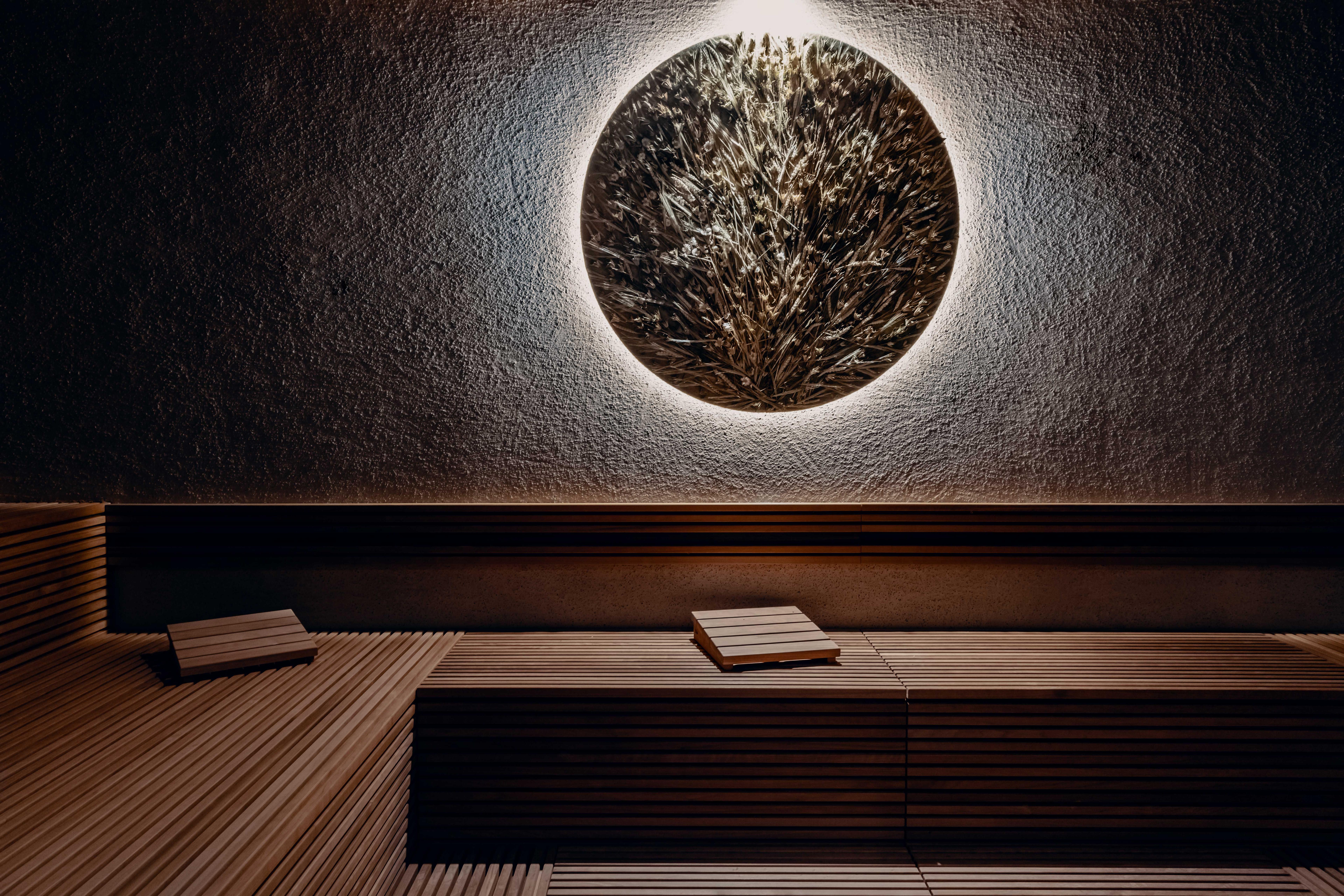 detail of a sauna with an illuminated round picture full of herbs and wildflowers.