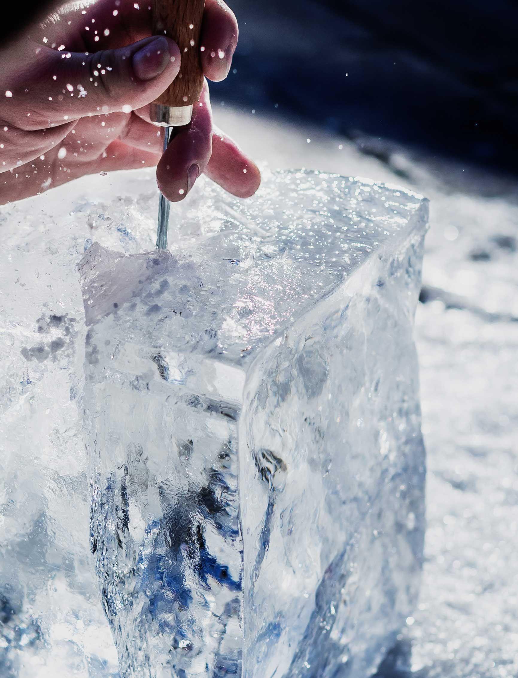 you can see a hand which breaks a block of ice with the help of special tools to make ice cubes for cocktails.