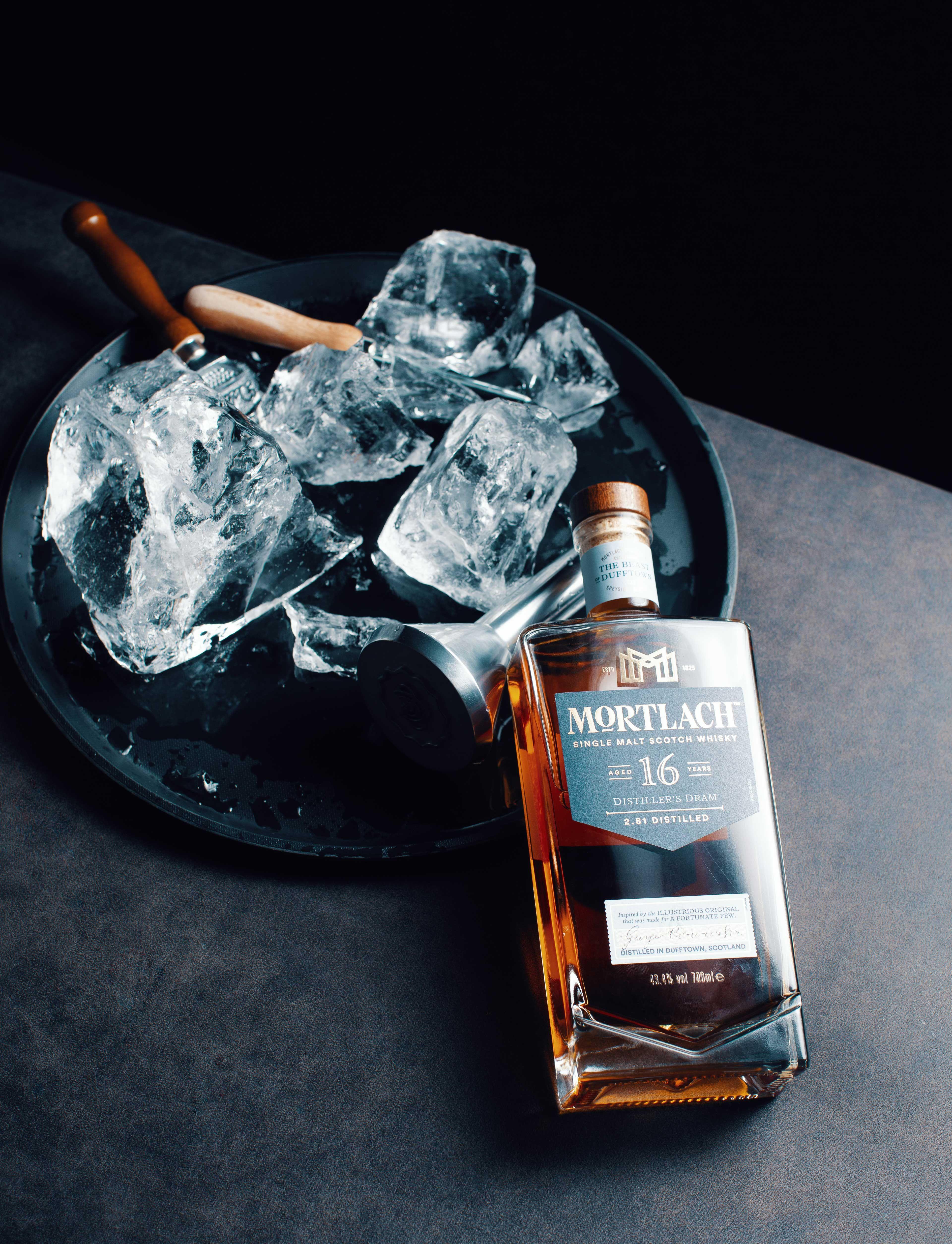 broken pieces of ice lie on a tray next to a bottle of mortlach scotch.