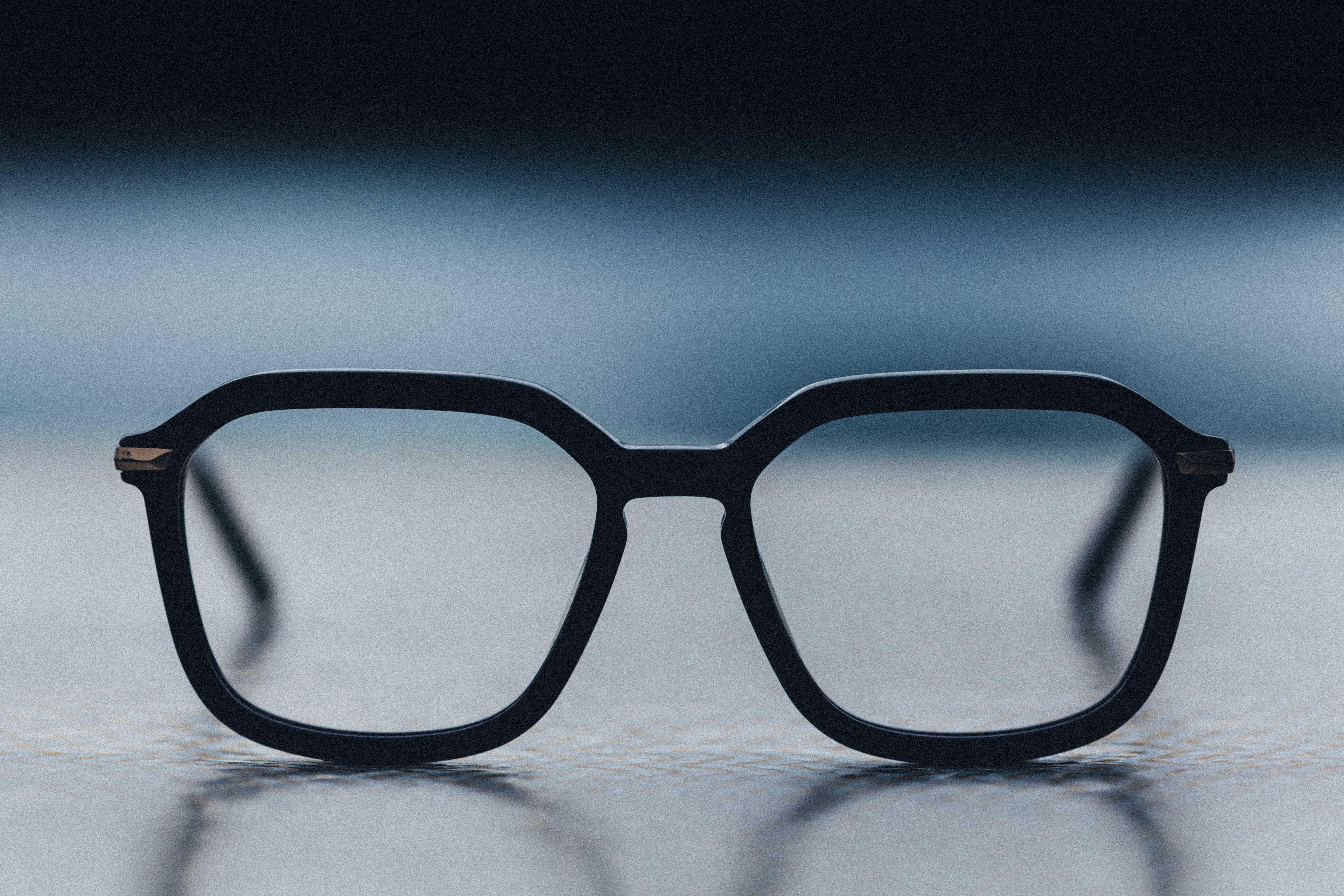 photograph of black optical glasses against black and blue gradient background.