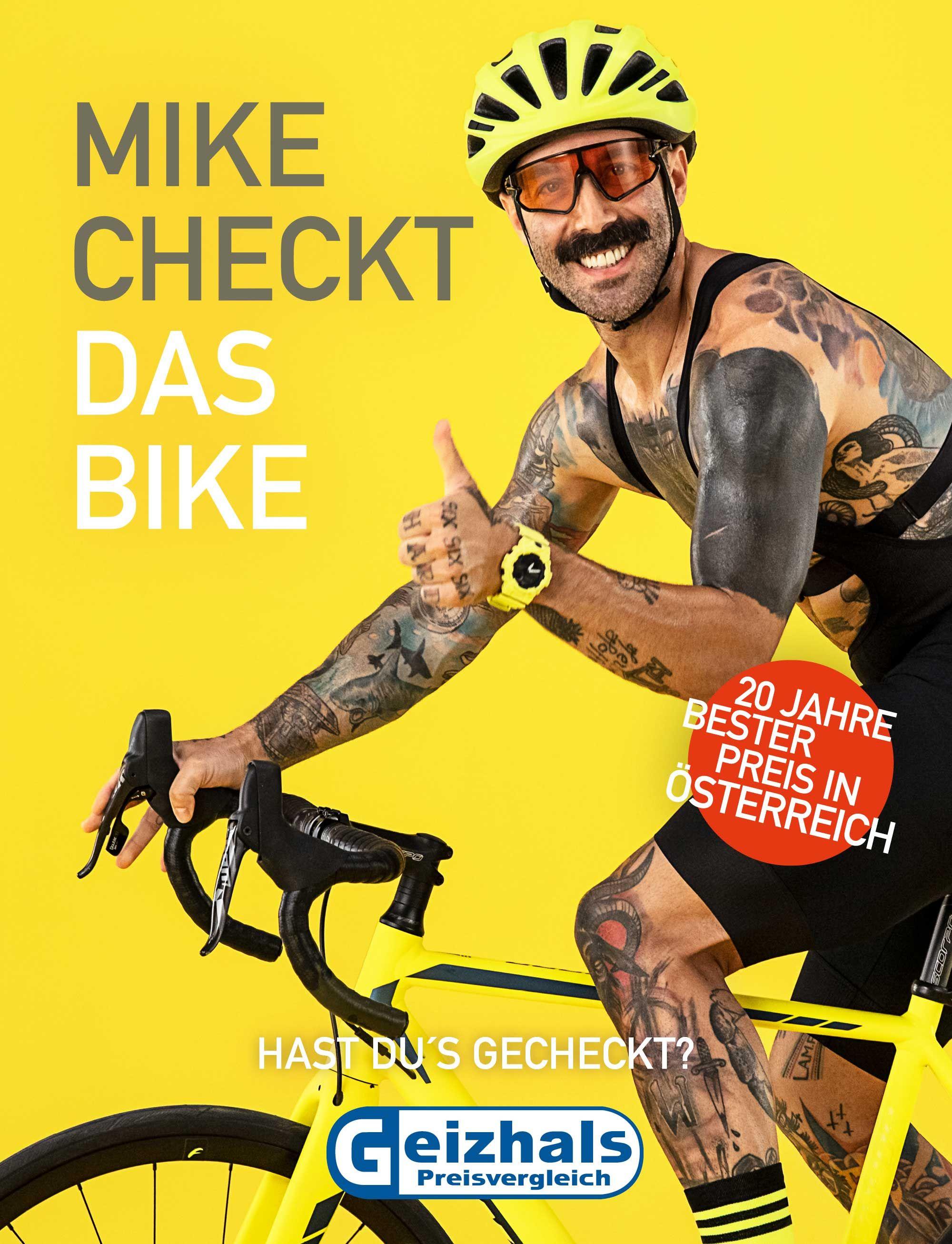 a young fully tattooed man sits on his racing bike and shows thumbs up while smiling broadly.