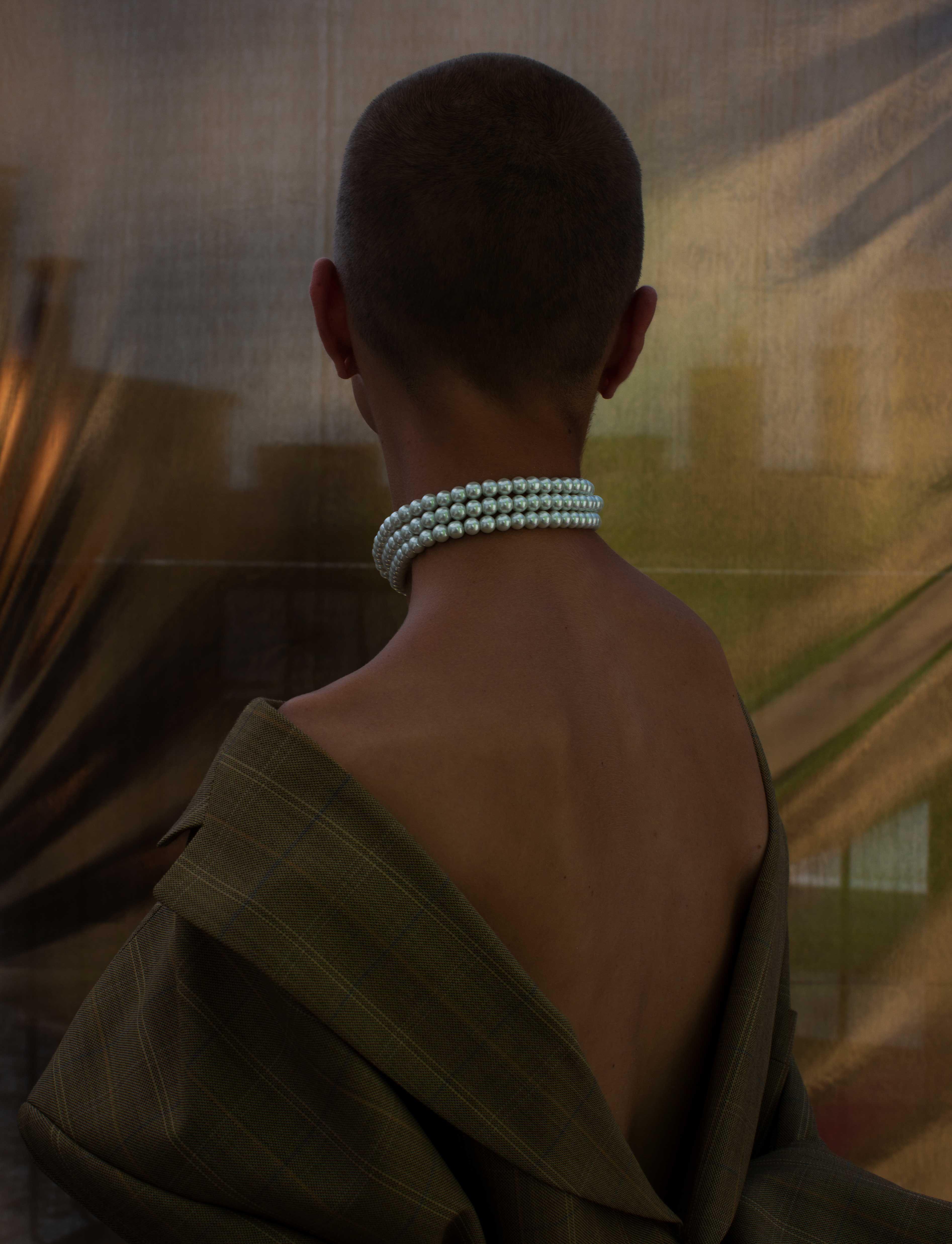 lost portrait of a woman with short cropped hair and a pearl necklace around her neck. 