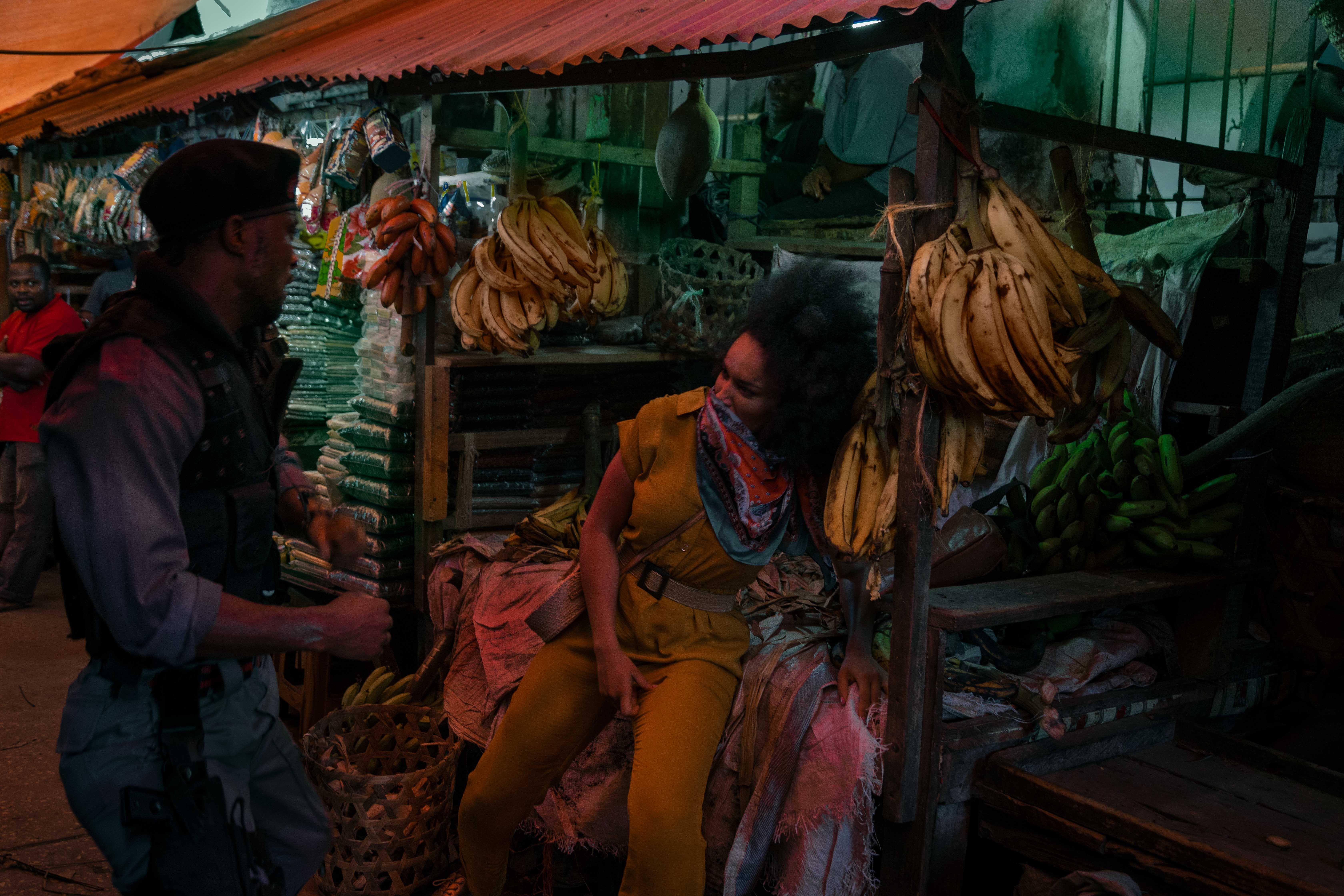 a woman falls onto a stand in the middle of a market hall after being beaten by a soldier.