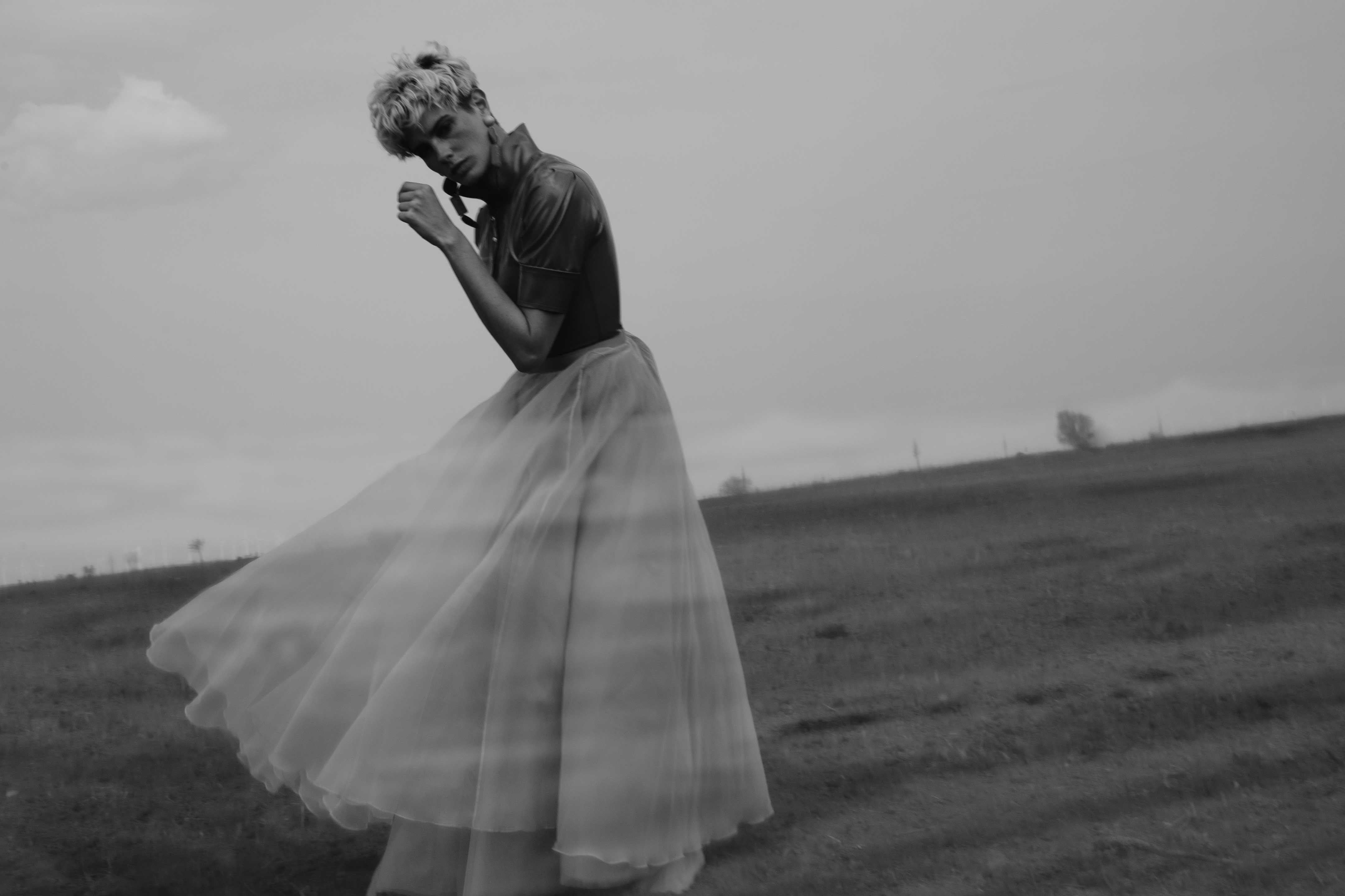 a woman stands in a voluminous tulle dress on a field.