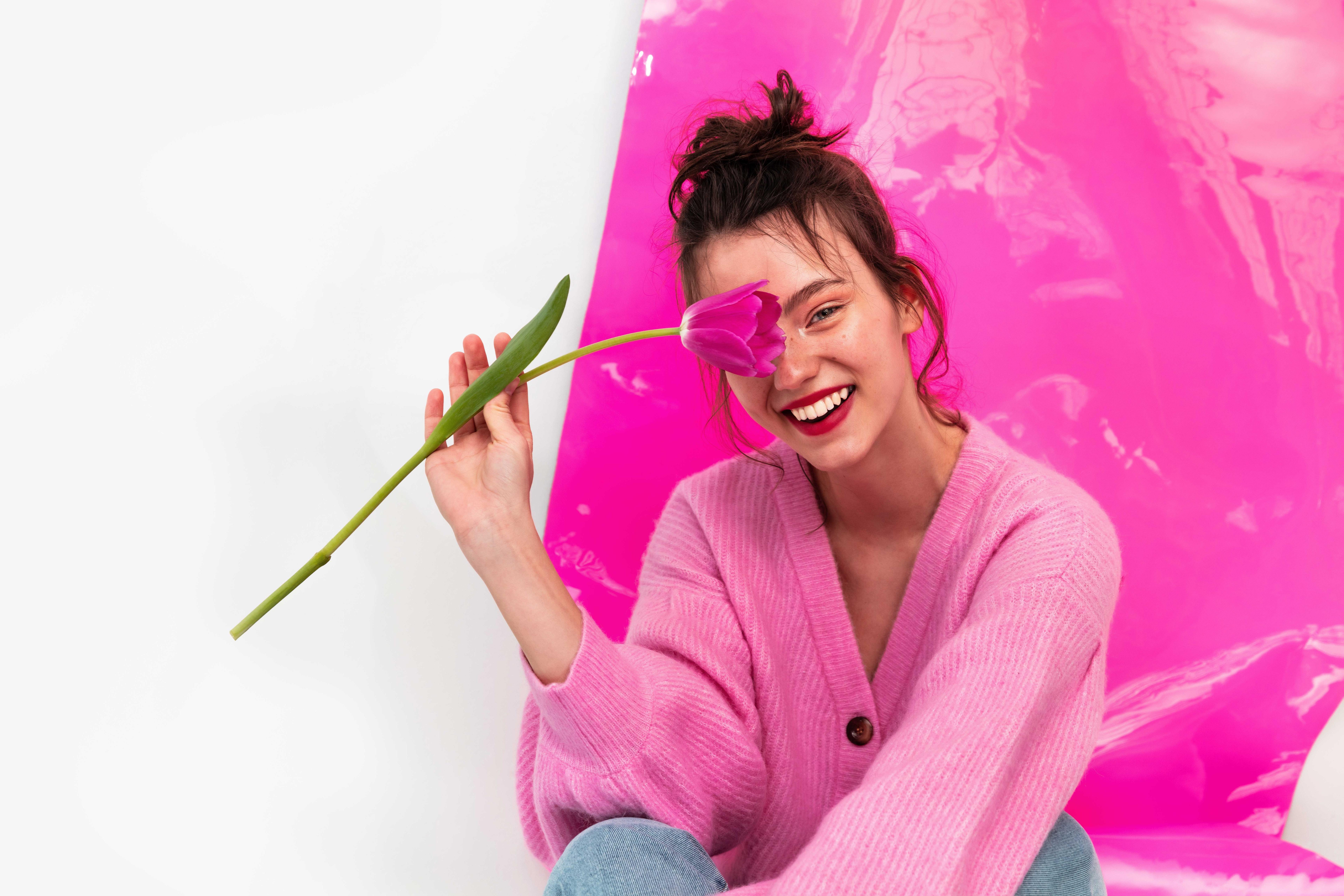 portrait of a woman with flower in hand sitting on the floor smiling.