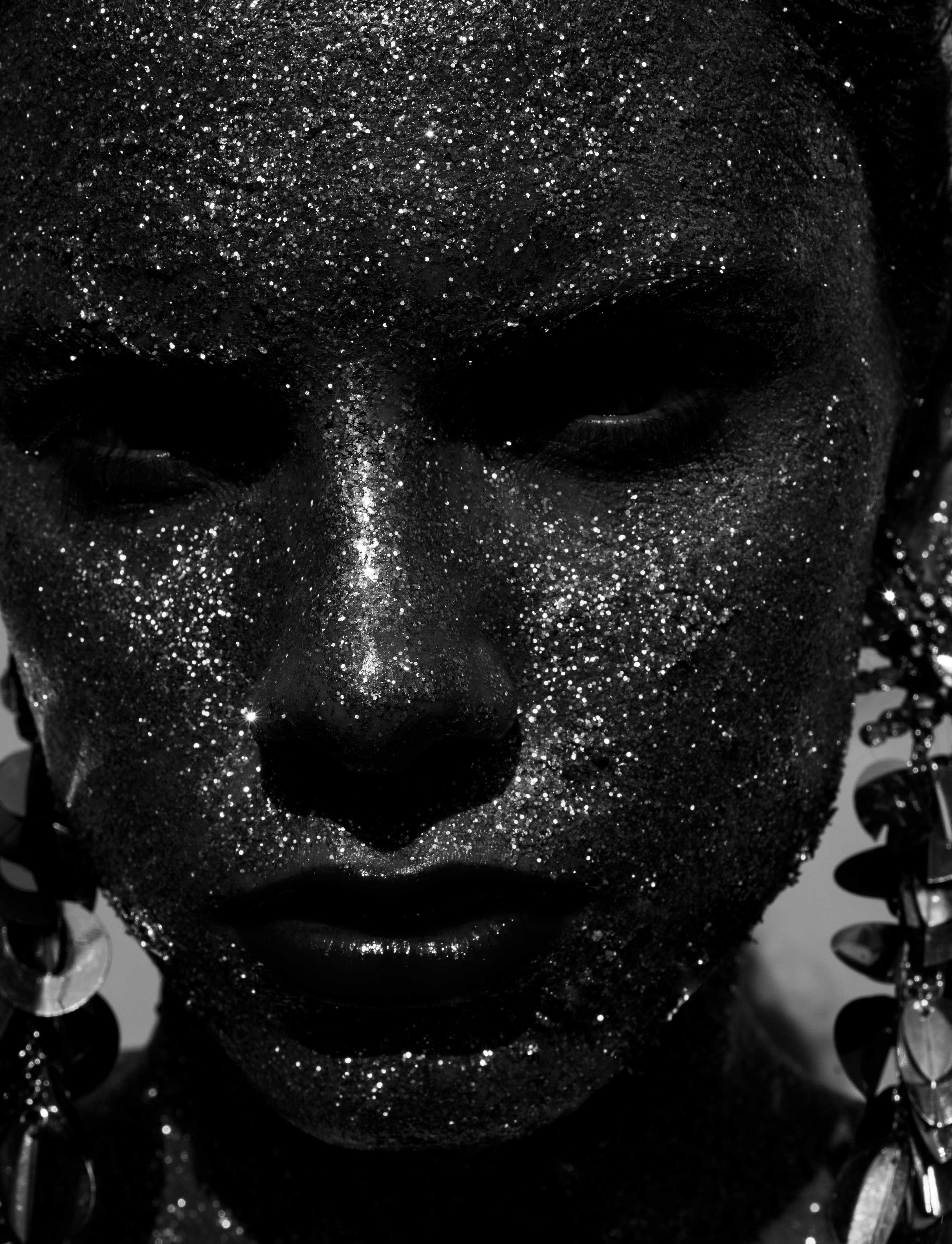 low keys black and white photo of a female face full of glitter.